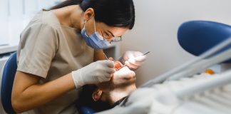 Group portrait of two people, woman dentist making treatment in modern clinic for man. Medical concept photography indoors for dentistry. Dental office, doctor working in clinic with patient.