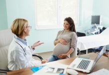 Happy expecting woman communicating with her female gynecologist during a visit in the office.